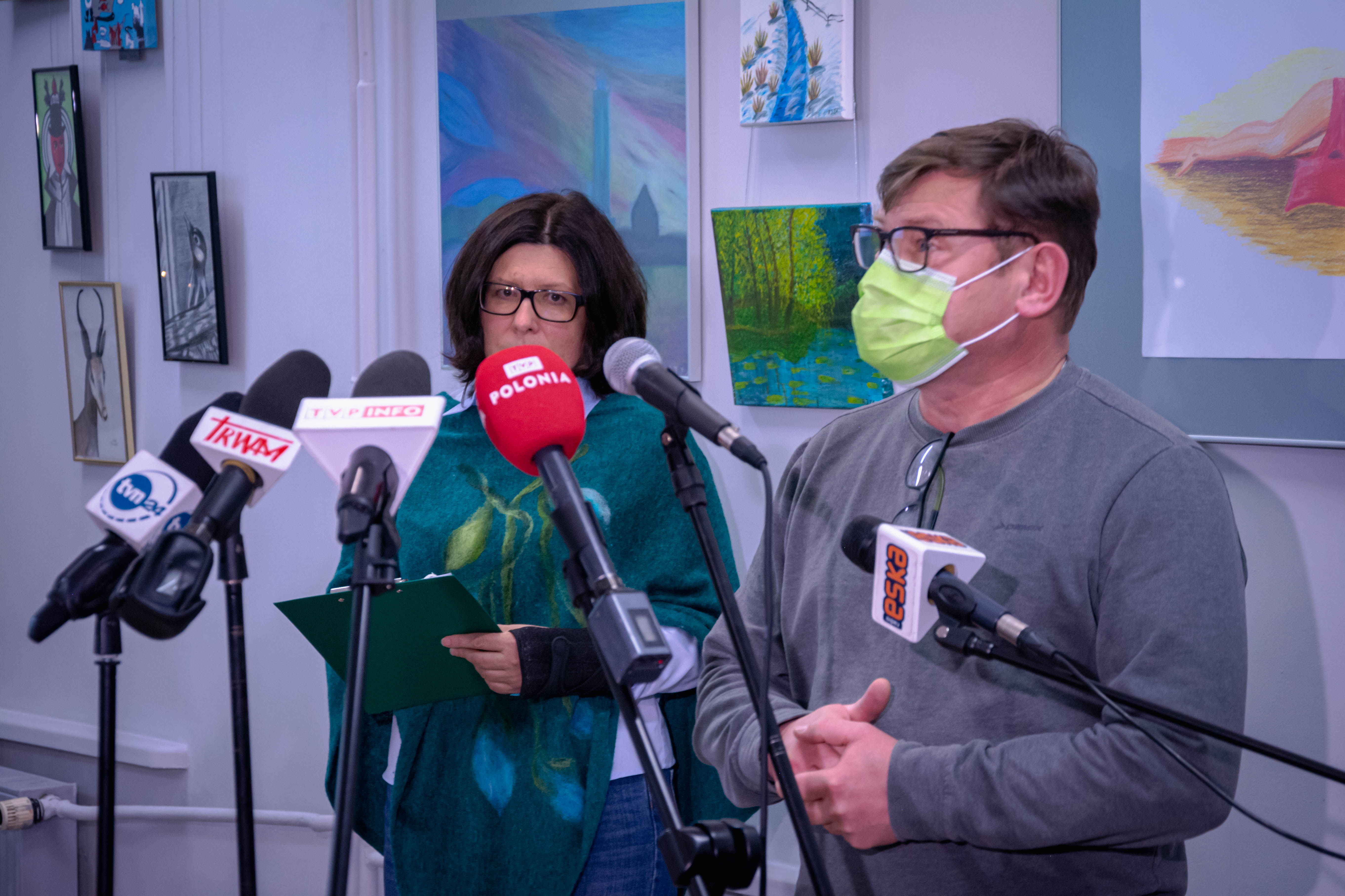 Dwie osoby stoją przy mikrofonach dziennikarzy