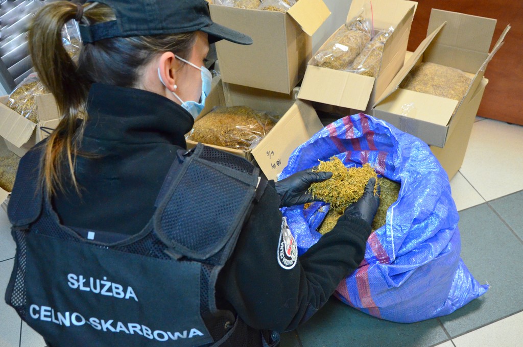 Funkcjonariusz KAS przy pudełkach z nielegalnym tytoniem