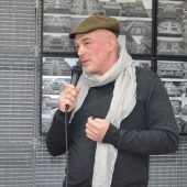 Kurator wystawy Gintaras Česonis na tle zdjęć