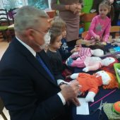 mężczyzna tworzy szmacianą lalkę przy stoliku w przedszkolu
