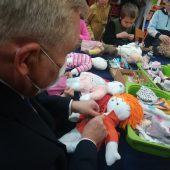 mężczyzna tworzy szmacianą lalkę przy stoliku w przedszkolu