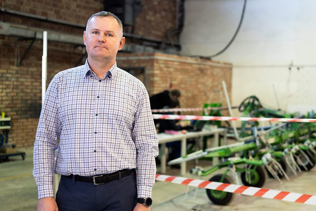 Mężczyzna stoi przy maszynie rolniczej