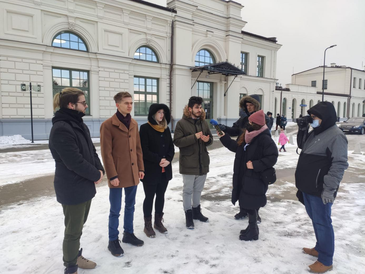 Młodzi ludzie stoją na terenie dworca PKP