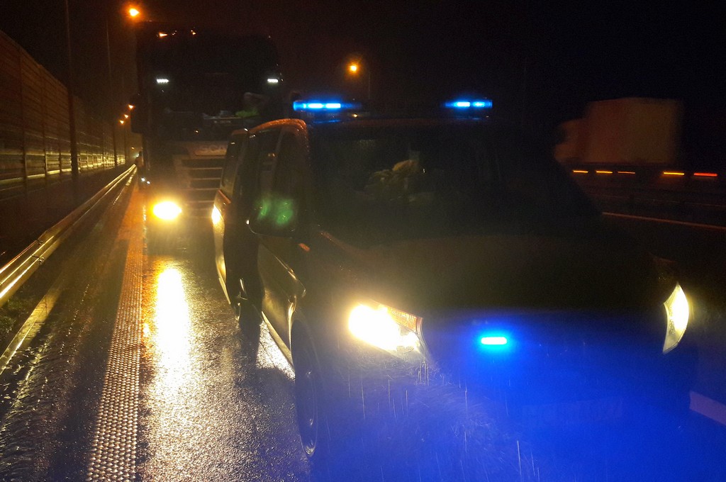 Droga szybkiego ruchu po zmroku. Na bocznym pasie stoi radiowóz, za nim zatrzymany tir