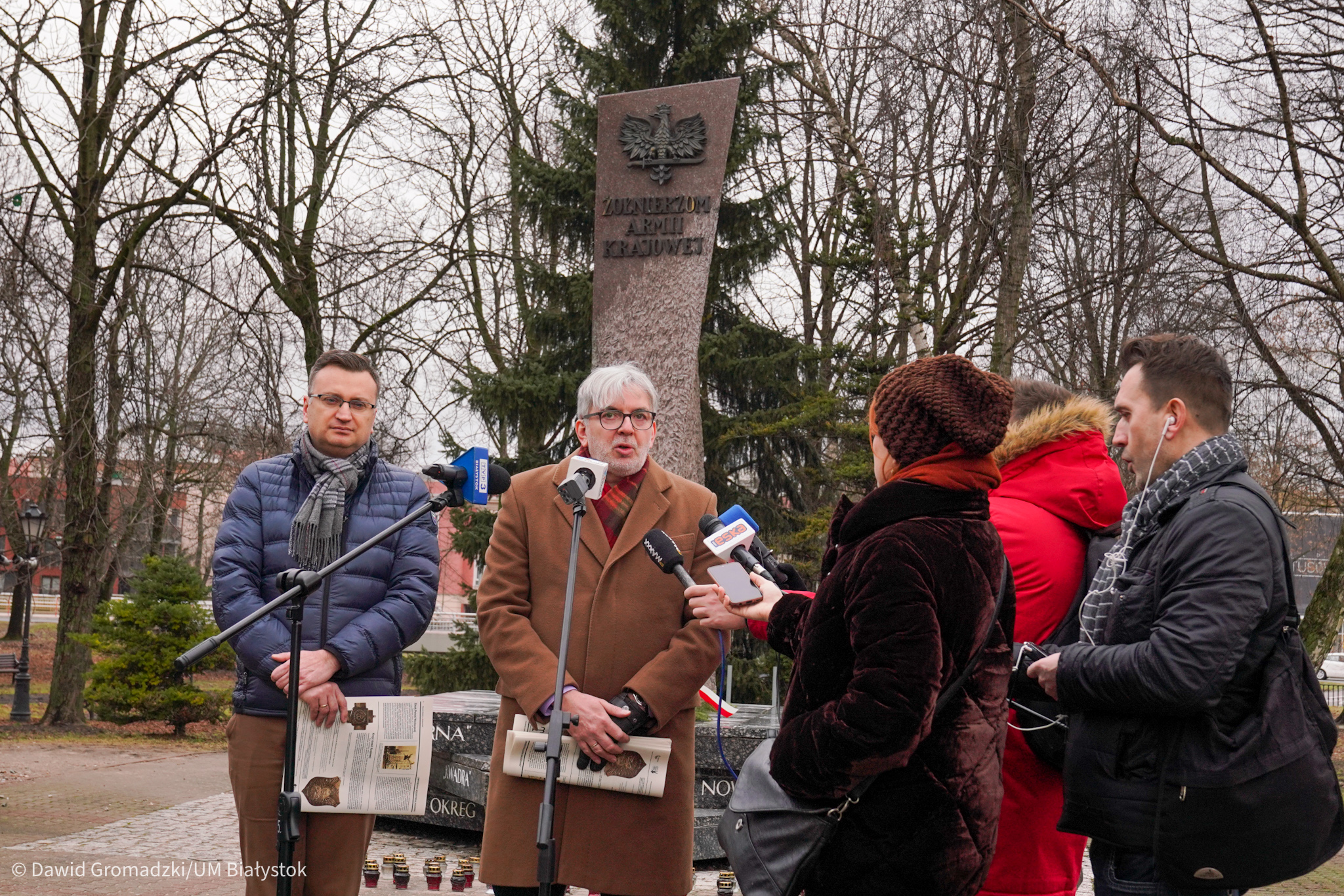 Konferencja prasowa, grupka ludzi stoi przy Pomniku AK