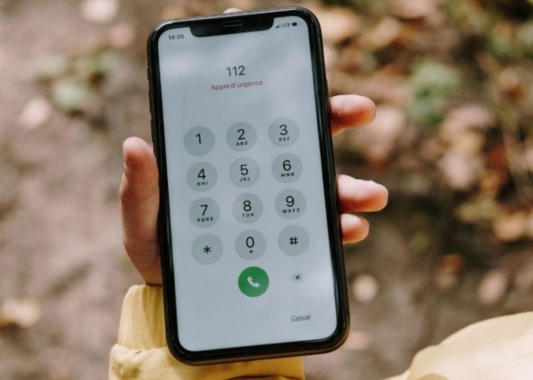 Kobieta trzyma w ręku telefon. Na wyświetlaczu widać nr 112