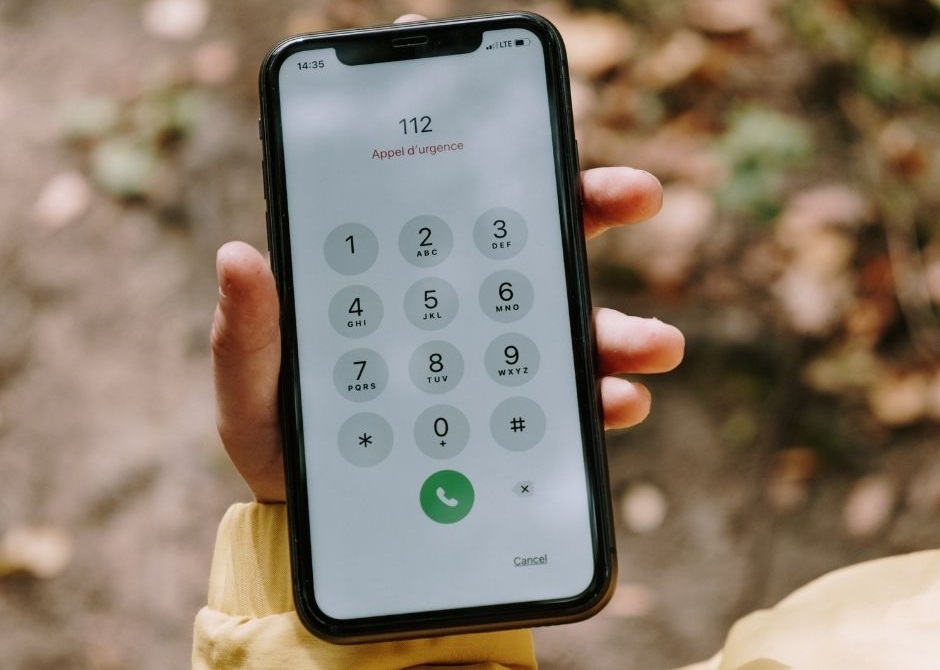 Kobieta trzyma w ręku telefon. Na wyświetlaczu widać nr 112