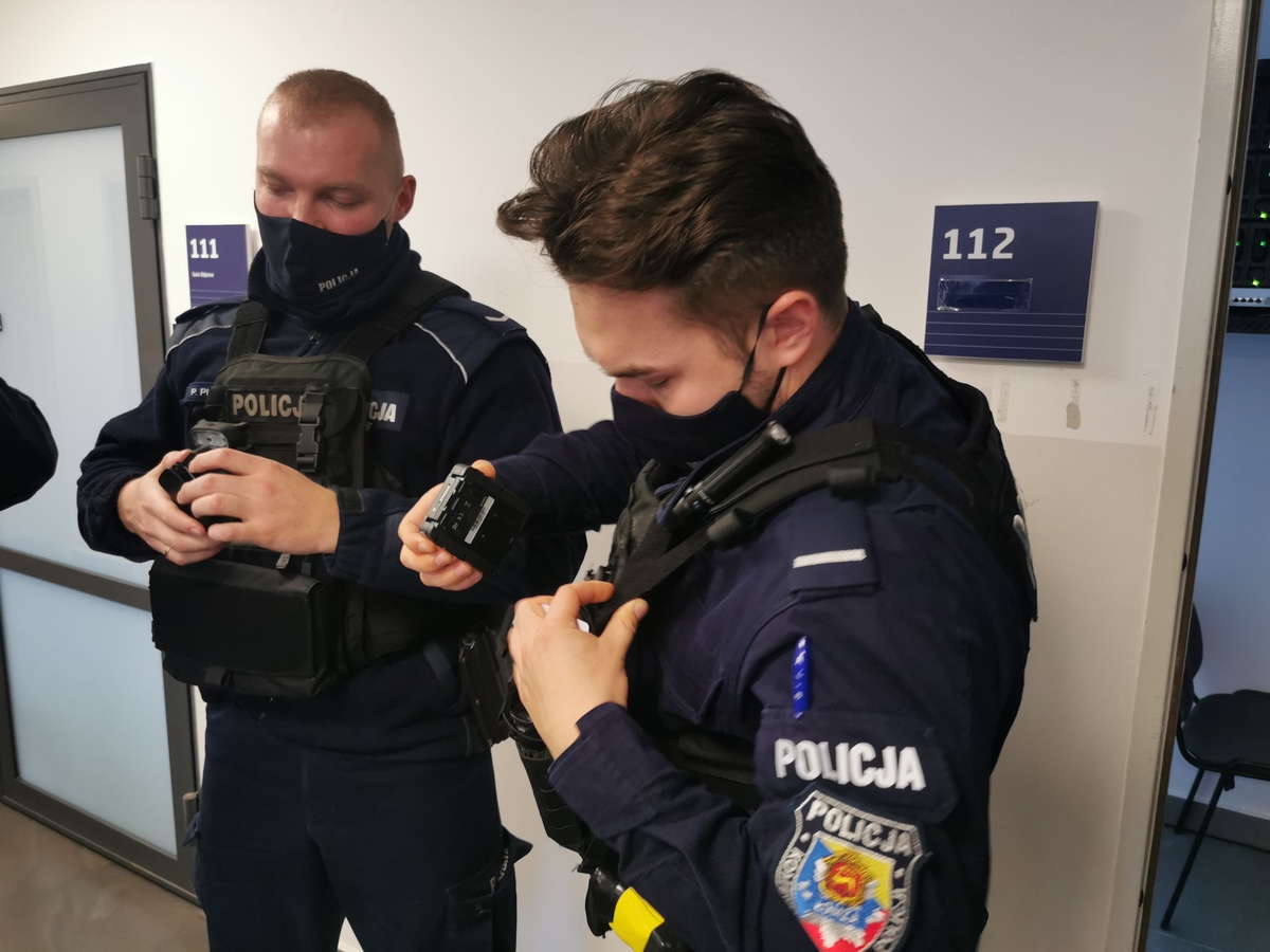 Dwaj policjanci mocują kamery do mundurów