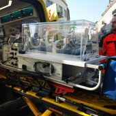 Inkubator w nowoczesnej karetce neonatologicznej. obok stoi ratownik