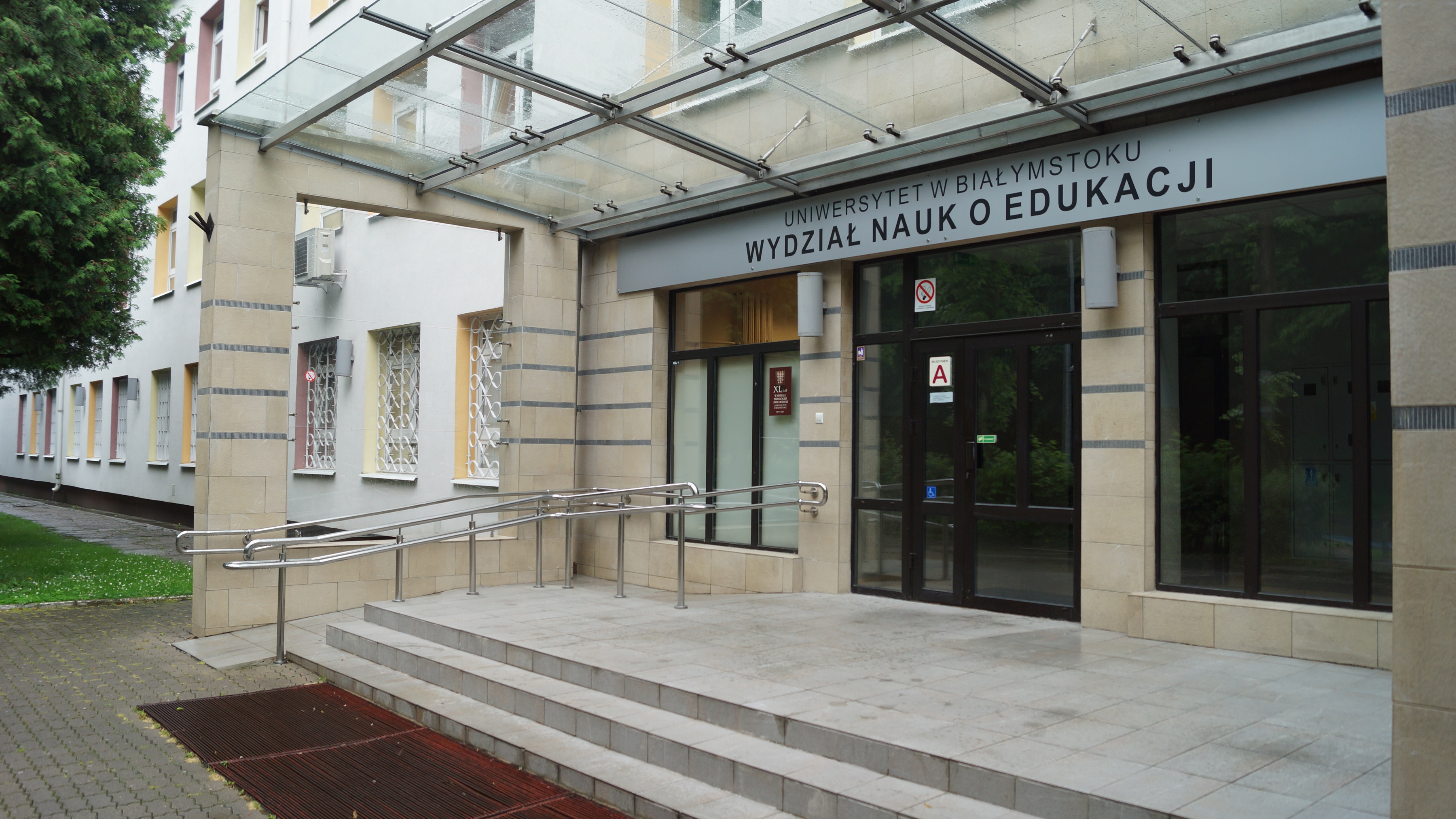 Wejście do budynku, do którego wchodzi się przez szklane drzwi, nad nimi znajduje się napis: Wydział Nauk o Edukacji