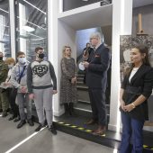 Ludzie stoją w muzeum podczas otwarcia wystawy, przemawia dyrektor