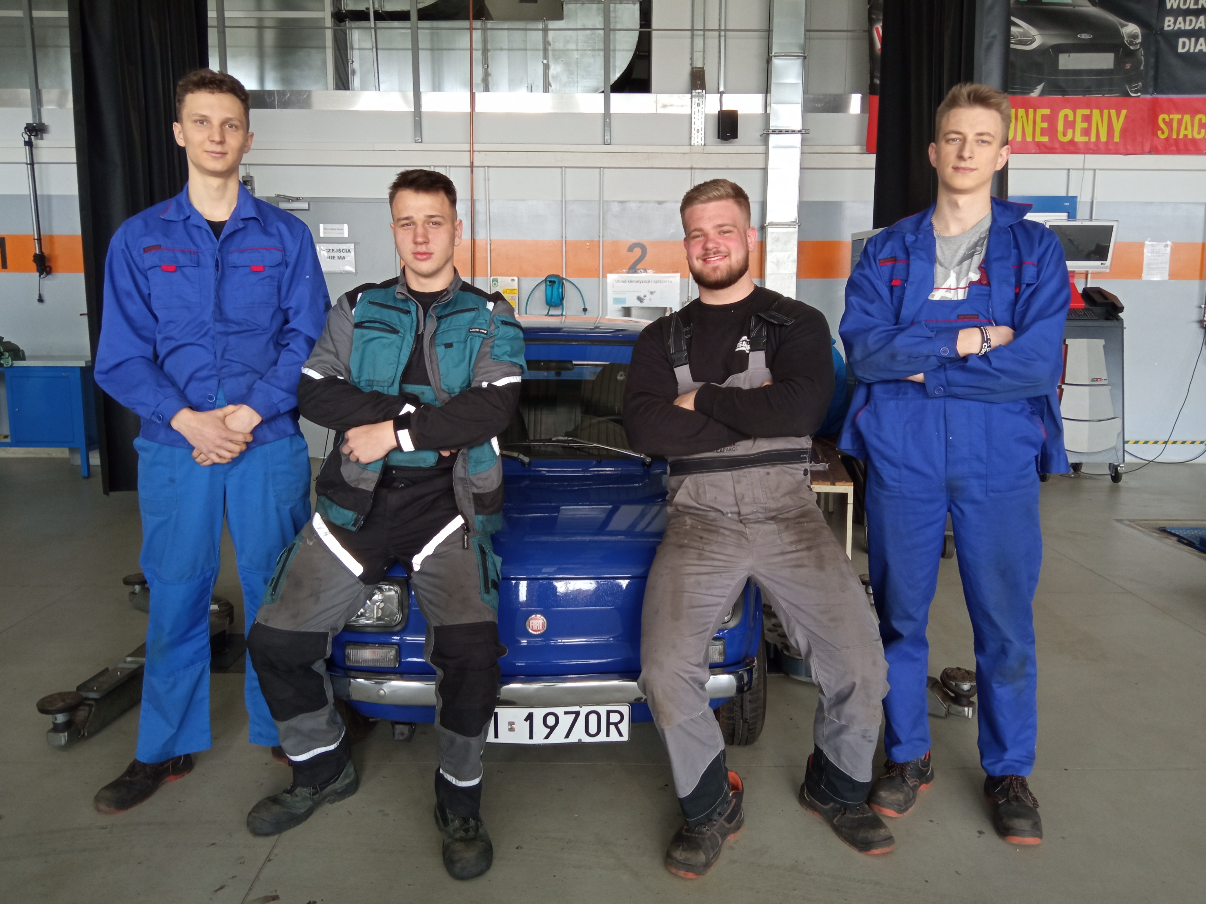 Uczniowei stoją przy zabytkowym samochodzie fiat 126p