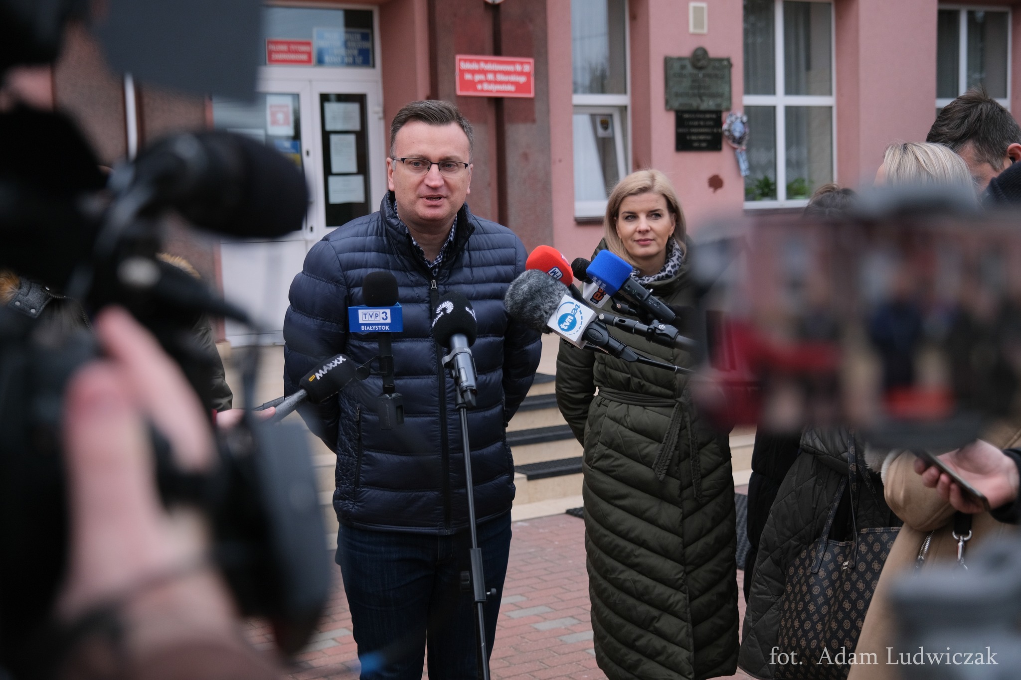Konferencja prasowa przed budynkiem szkoły, do mikrofonu mówi wiceprezydent Białegostoku