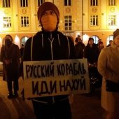 Mężczyzna stoi z transparentem. Wokół ludzie