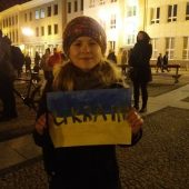 Dziewczynka stoi z namalowaną własnoręcznie ukraińska flagąa