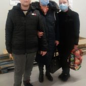 Chłopiec i dwie kobiety - uchodźcy z Ukrainy stoją w punkcie darów na stadionie