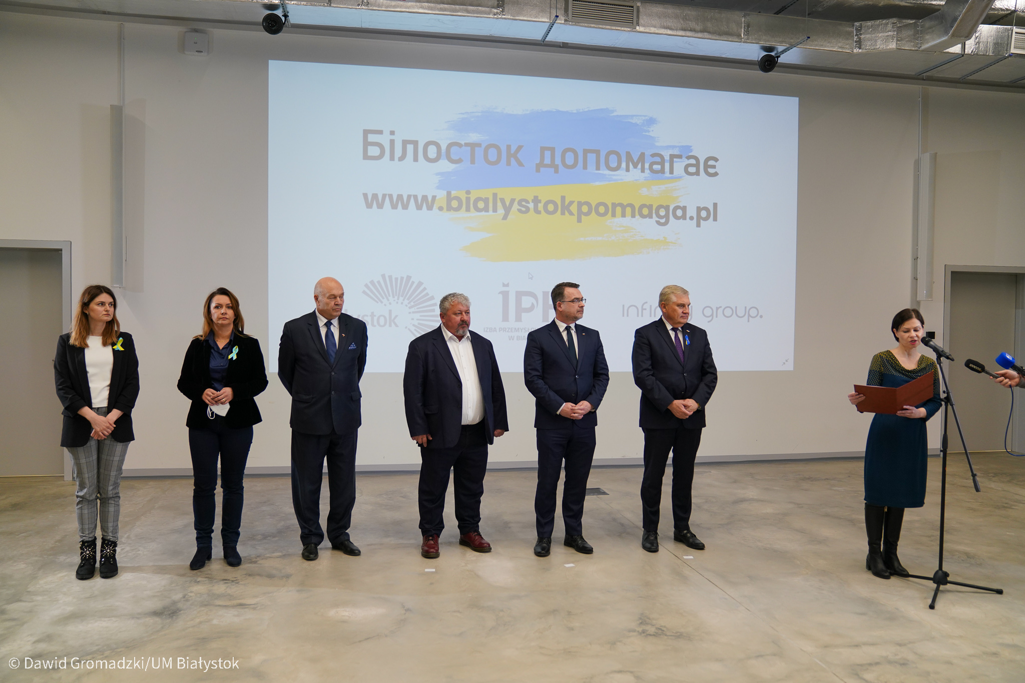 Ludzie stoją na tle wyświetlonej strony internetowej