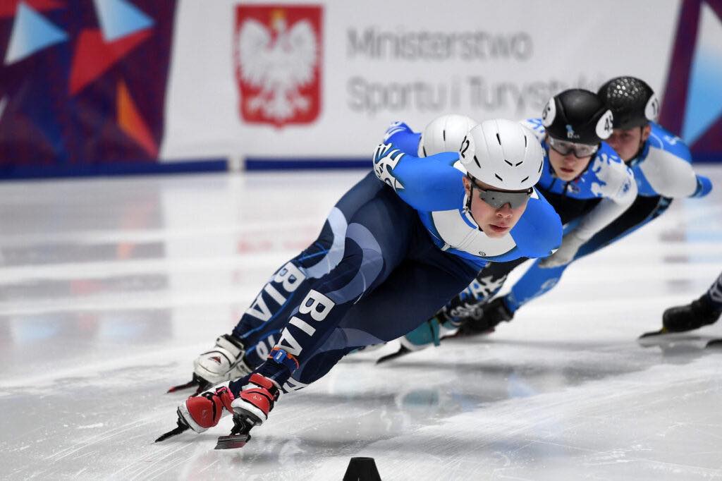 Zawodniczki short-tracka, w niebiesko-czarnych kombinezonach jadą, jedna za drugą po tafli lodu