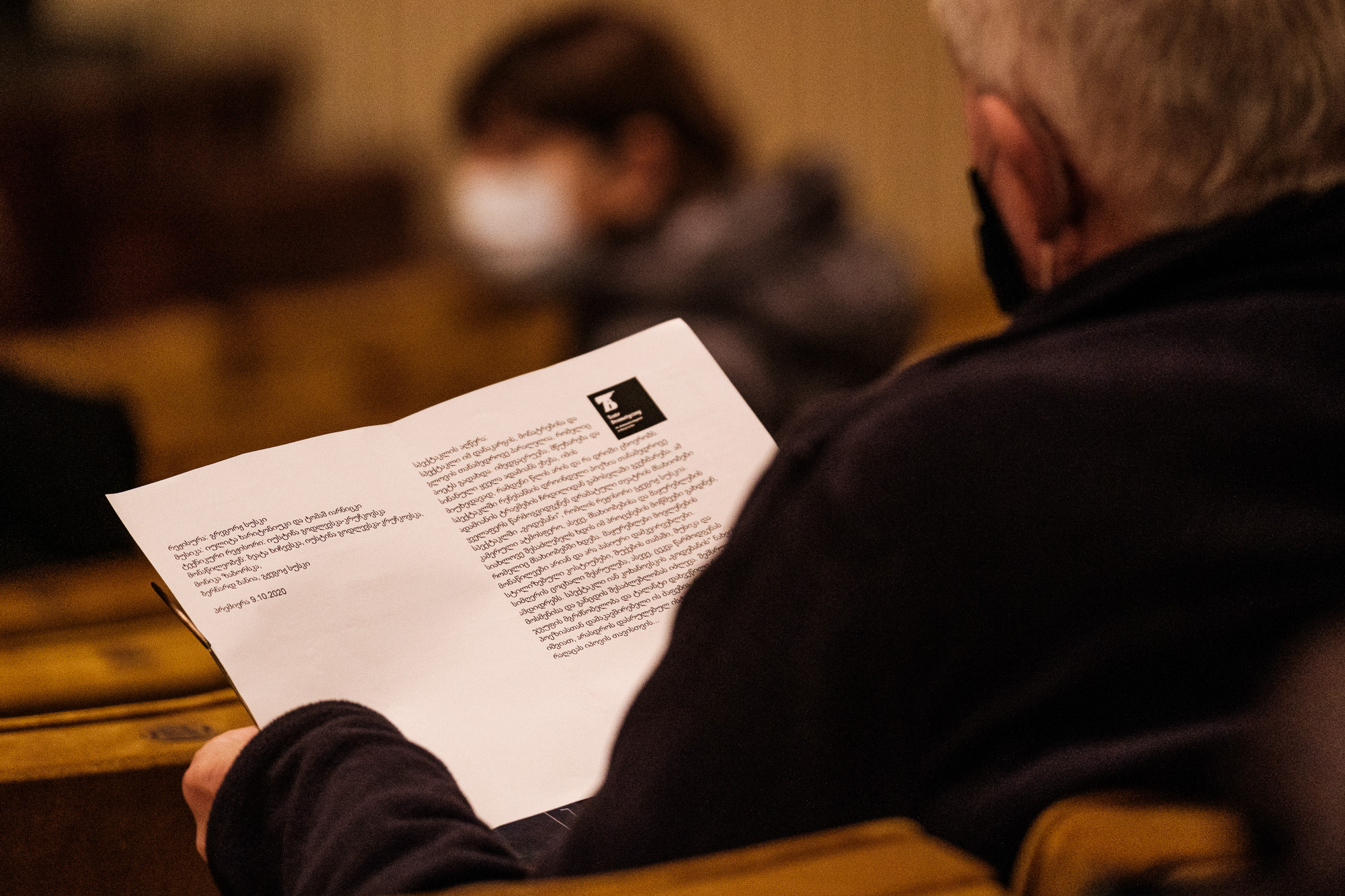 Mężczyzna siedzący tyłem na widowni przegląda program festiwalu Kierunek Wschód