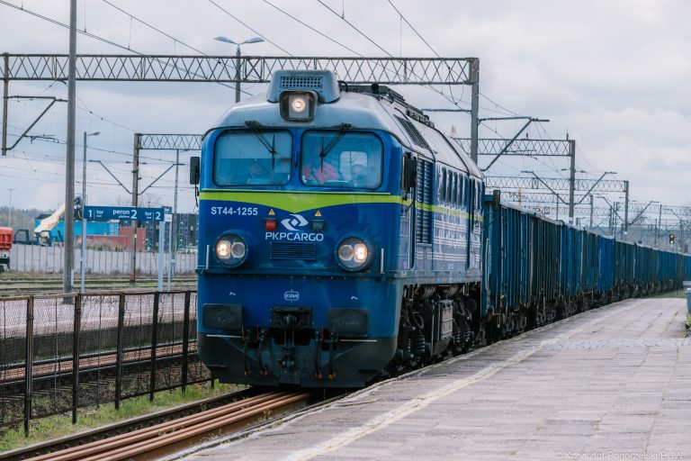 Niebiesko-zielony pociąg towarowy jedzie po torach