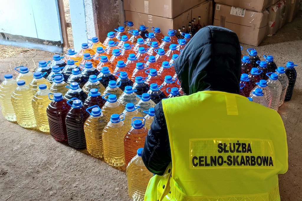 Funkcjonariusz KAS przy butelkach z alkoholem