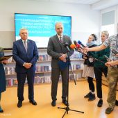 Mężczyna mówi do mikrofonu, obok stoi mężczyzna, kobieta i osoby z mikrofonami
