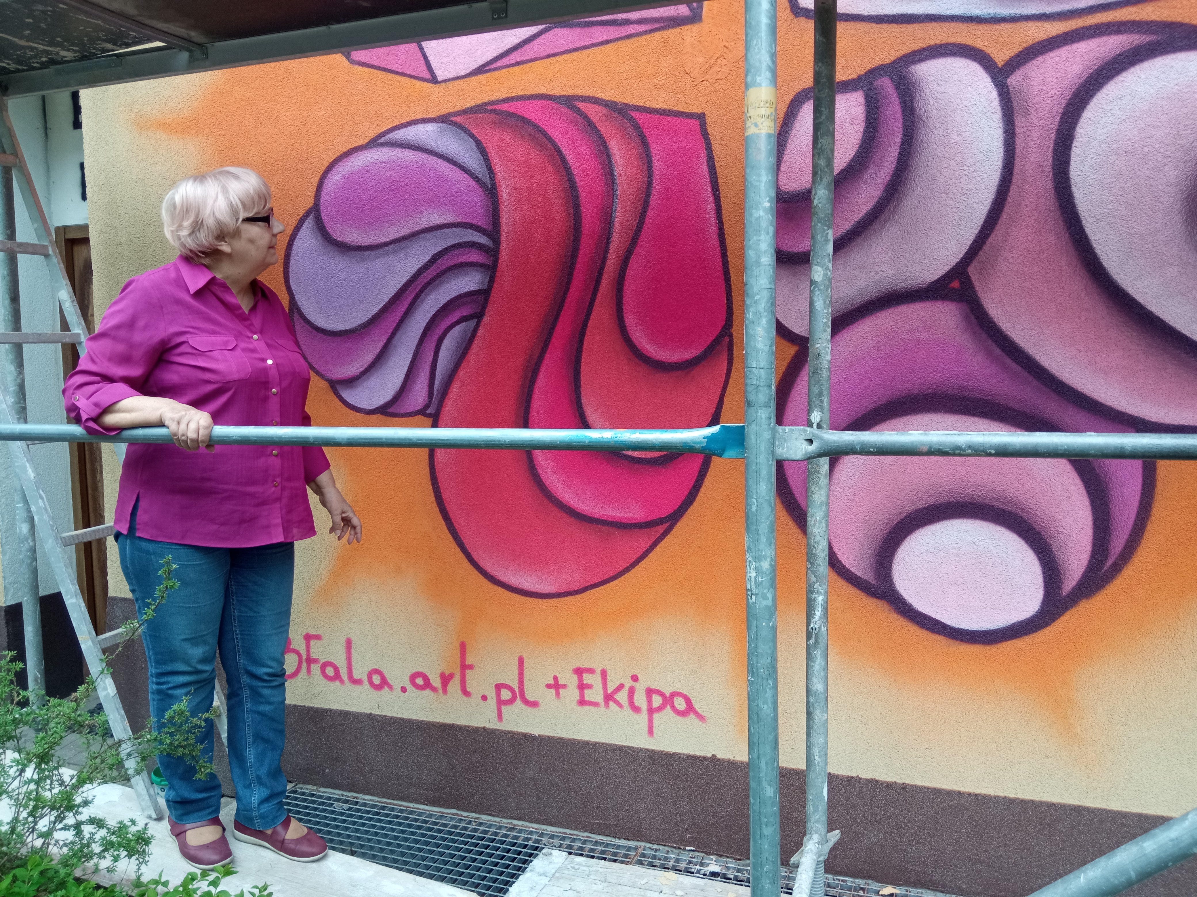 Kobieta ogląda Kolorowy mural na ścianie budynku