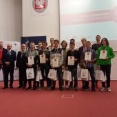 Grupa uczniów i profesorów stoi na podium