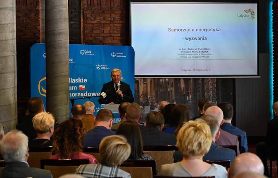 Odbywa się kongres, sala pełna ludzi, przy mównicy stoi mężczyzna i mówi do mikrofonu