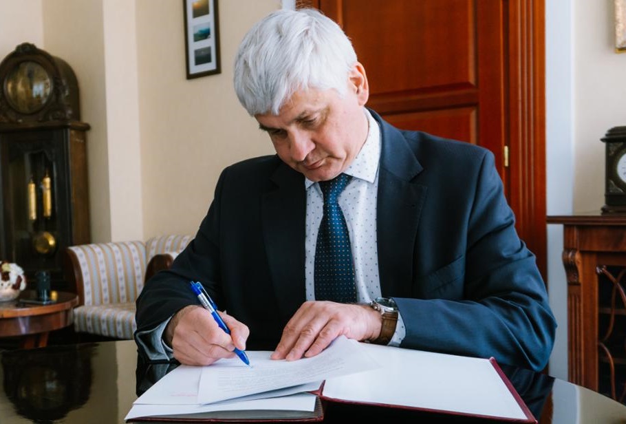Siwy mężczyzna podpisuje dokumenty przy biurku