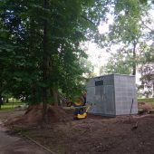 Na ziemi stoi budynek toalety, wokół trwają prace