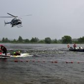 Ratownicy na motorówce ćwiczą ratowanie topiącego się człowieka. W pobliżu lata helikopter