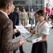 Mężczyzna wręcza dyplom i nagrody dziewczynce