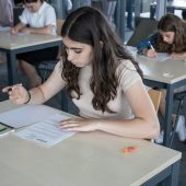 Uczennice przy stolikach rozwiązują zadania
