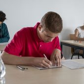 Uczniowie przy stolikach rozwiązują zadania