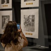 Kobieta fotografuje grafiki na wystawie