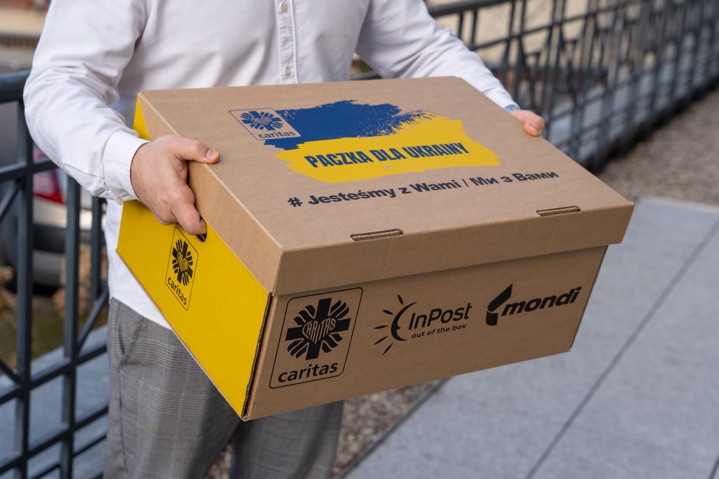 Mężczyzna trzyma karton z napisem Paczka dla Ukrainy