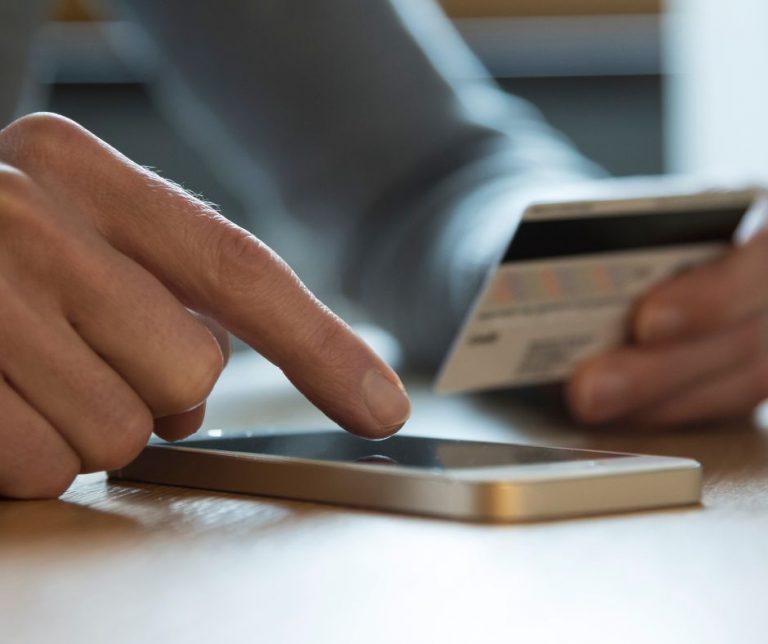 Męźczyzna paci kartą przez aplikację telefoniczną