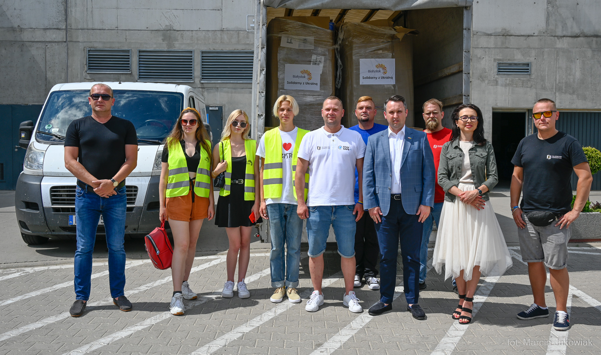 Ludzie stoją na tle załadowanego darami samochodu