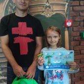 Mężczynza stoi z córką. Trzymają plecak szkolny i blok rysunkowy