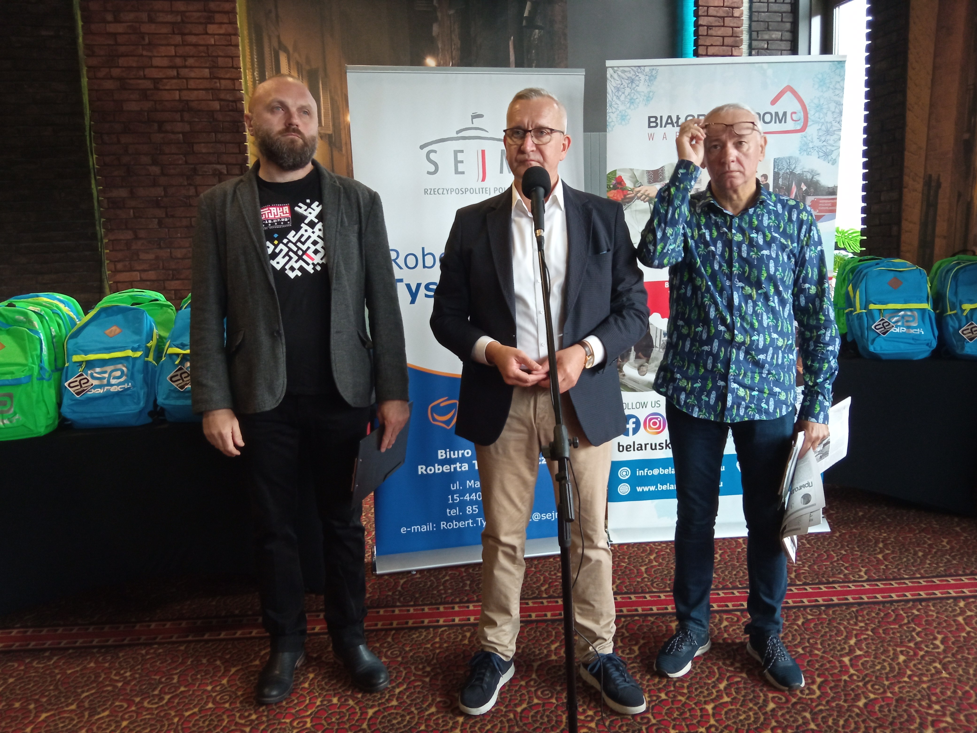 Trzech mężczyzna stoi na konferencji prasowej