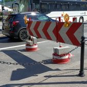 Zwężona ulica, po jednym pasie jadzie samochód osobowy, obok autokar