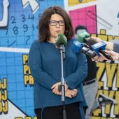 Elegancka kobieta mówi do mikrofonu na statywie i mikrofonów trzymanych w ręku