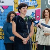 Elegancka kobieta mówi do mikrofonu na statywie i mikrofonów trzymanych w ręku