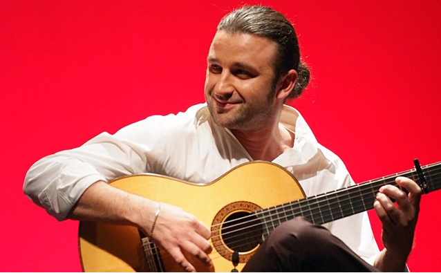 mężczyzna z długimi włosami gra na gitarze