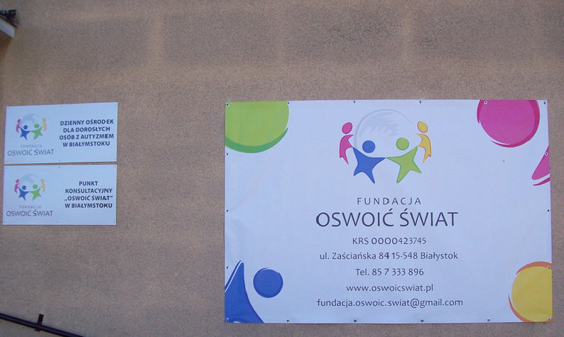 baner na ścianie z napisem oswoić świat