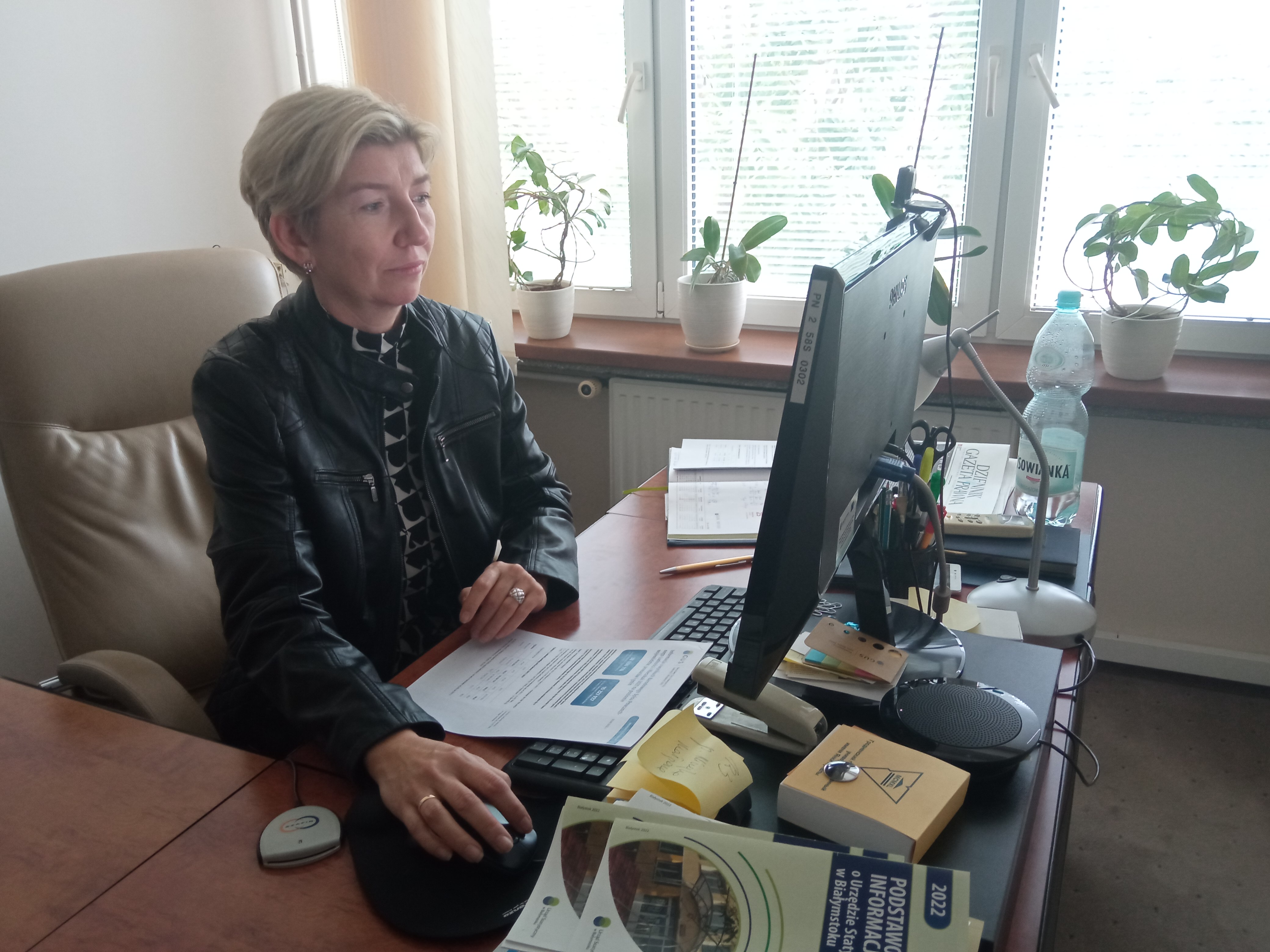 Kobieta siedzi za biurkiem przed komputerem