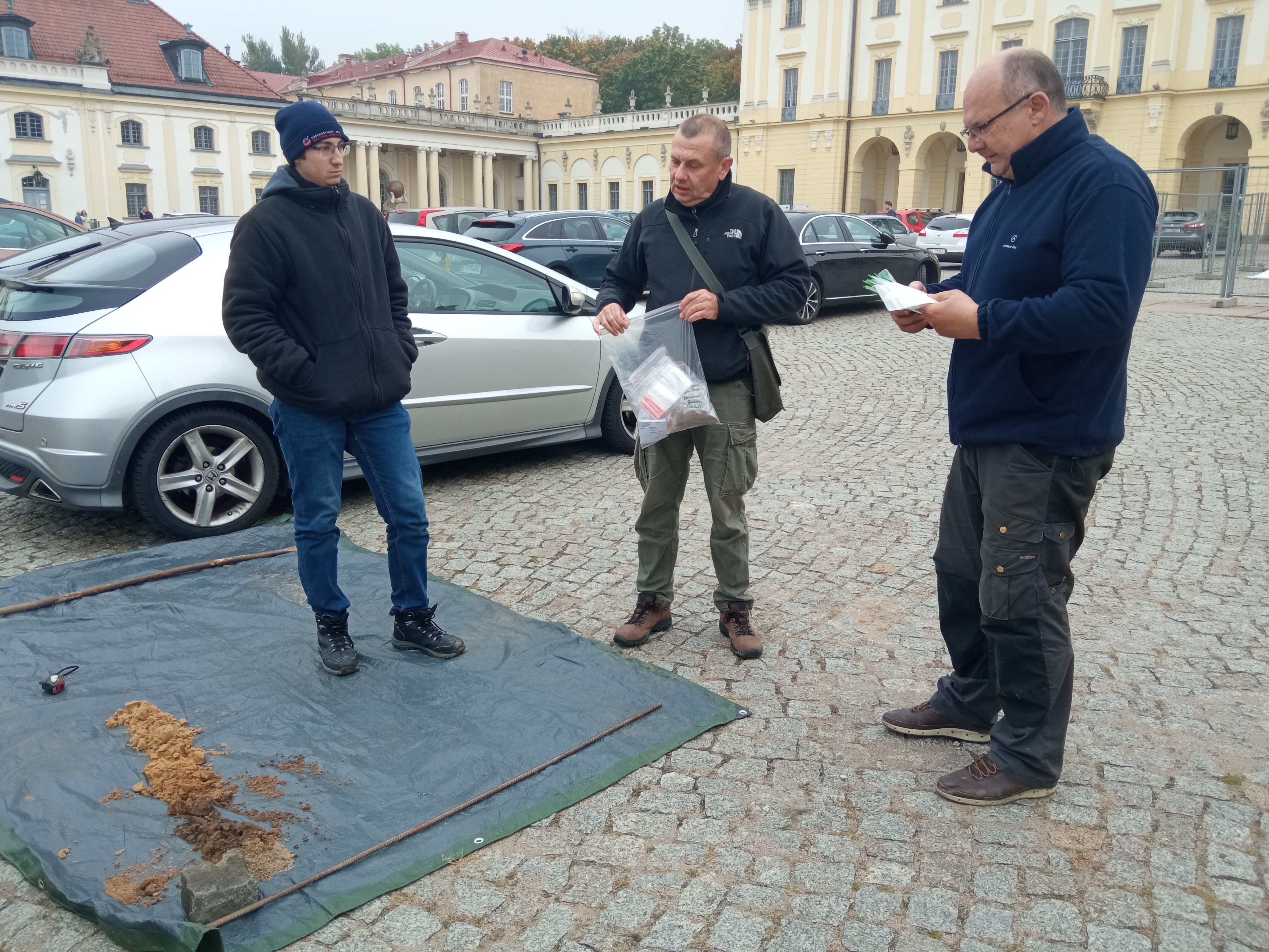 Trezch mężczyzn stoi obok małego odwiertu