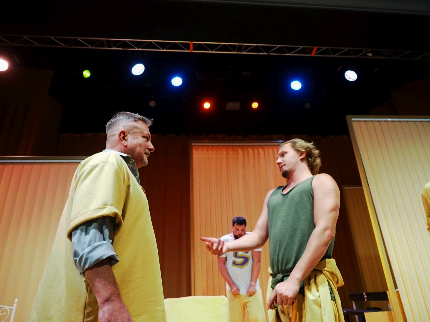 Dwóch mężczyzn patrzy sobie w twarz na scenie teatralnej