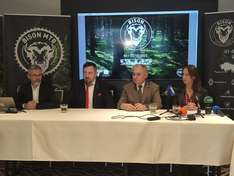 Cztery osoby siedzą za stołem, na którym stoją mikrofony